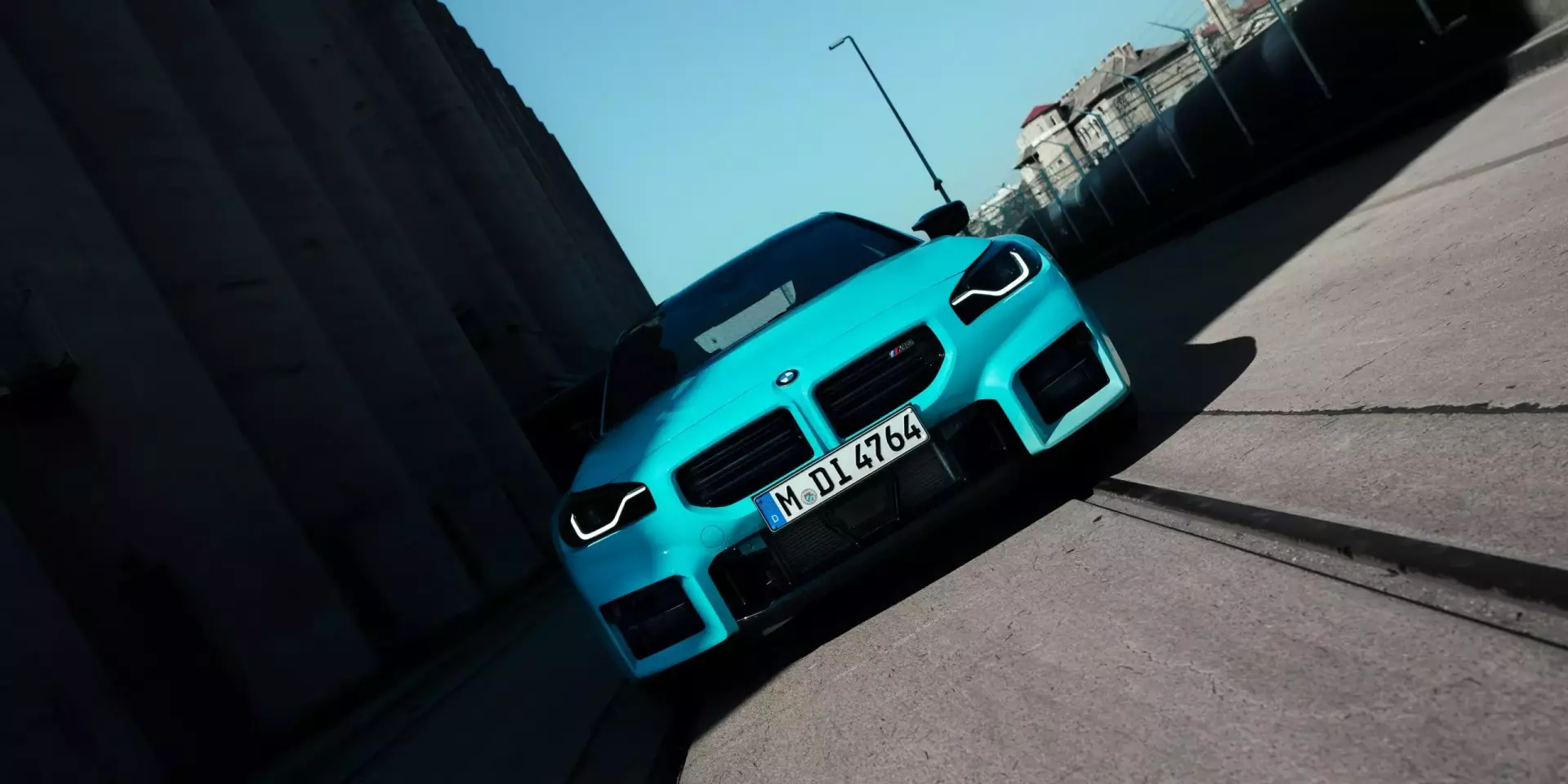 Ein BMW M2 mit M xDrive in der Farbe Borusan Turkish Blau fährt in einem Industriegebiet auf den Straßen mit Gleisen.
