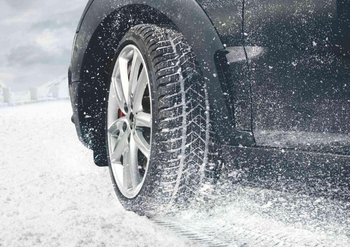Der linke Vorderreifen eines MINI mit Alufelgen im 10-Speichen Design im Schnee.