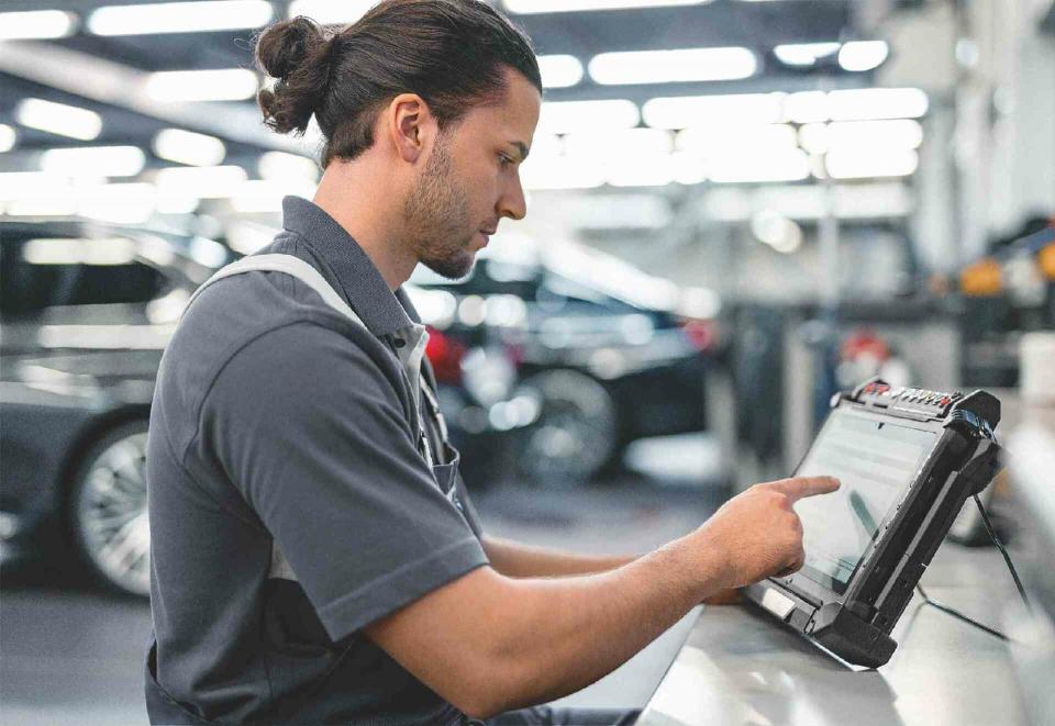 Ein Mitarbeiter einer BMW Werkstatt prüft den Fehlerspeicher eines Fahrzeuges.