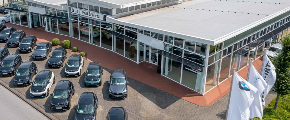 Der Eingang des Autohauses Fett & Wirtz in Moers mit davor parkenden BMW Fahrzeugen.