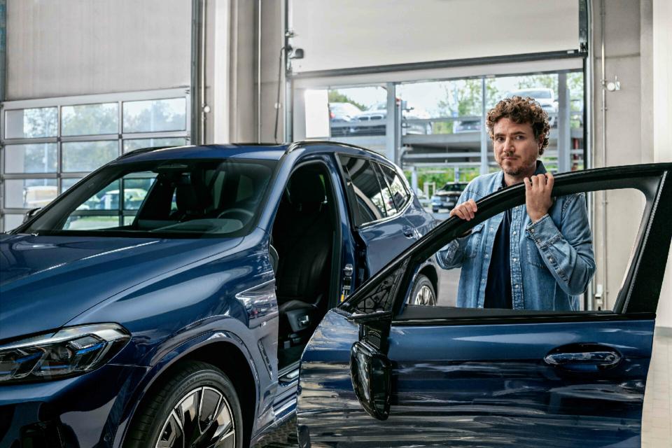 Ein Kunde holt seinen BMW nach dem reparierten Hagelschaden ab und steigt gerade ins Fahrzeug ein.