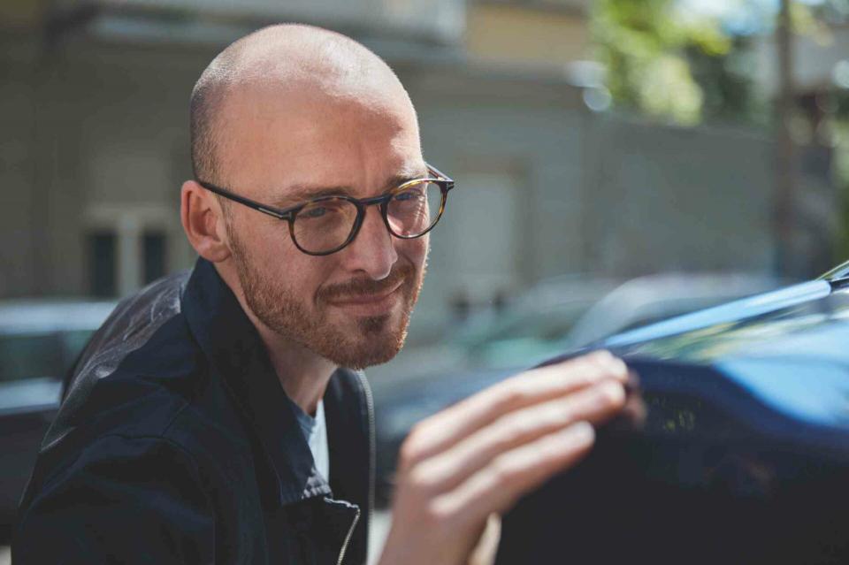 Ein Kunde betrachtet den glänzenden schwarzen Lack am Heck seines BMW.