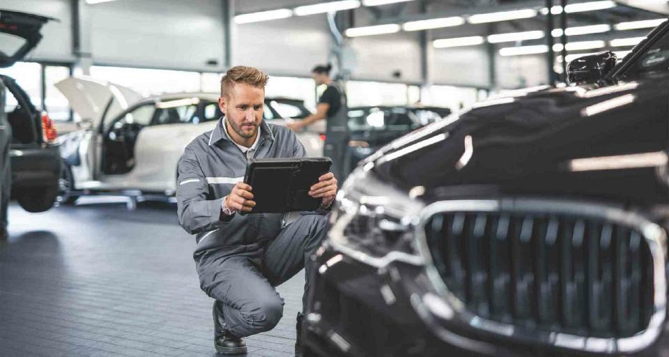 Ein Servicemitarbeiter einer BMW Werkstatt fotografiert die Vorderseite eines BMW.