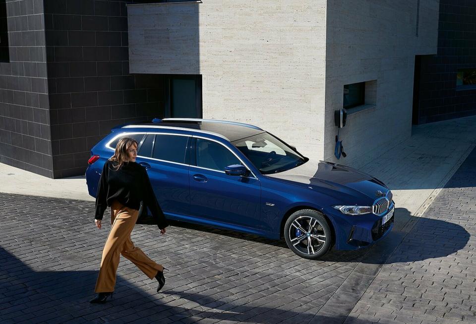 Eine Businessfrau schreitet an einem BMW 3er in "transitblau metallic" vorbei und blickt zurück.