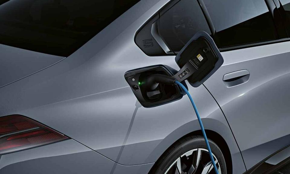Ein 5er BMW Plug-in Hybrid in der Farbe 'storm bay metallic' wird an einer Stromtankstelle aufgeladen.
