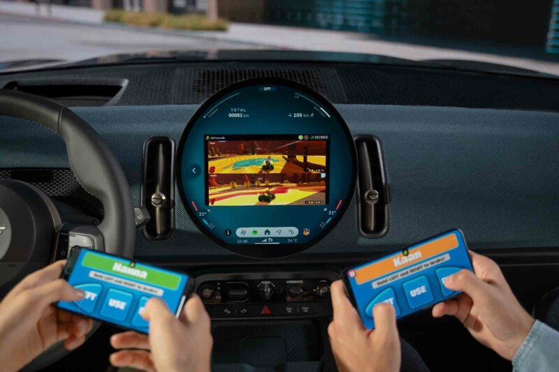 Zwei Personen spielen mit ihren Smartphones ein Spiel auf dem zentralen Display in einem MINI 3-Türer.
