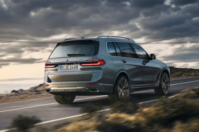 Ein BMW X7 xDrive40i fährt auf einer Landstraße in einer Bergregion.