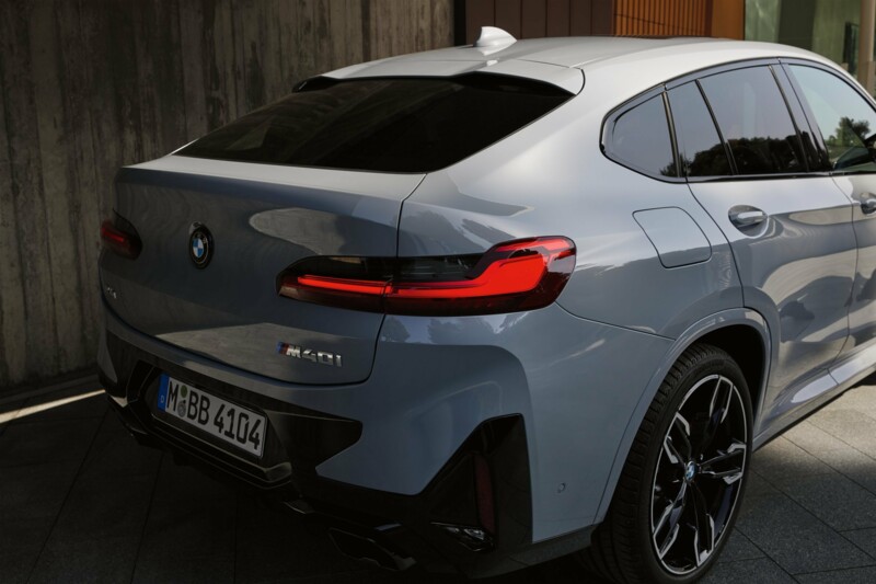 Ein BMW X4 M Competition in der Farbe Nardograu metallic parkt an einem Mehrfamilienhaus.