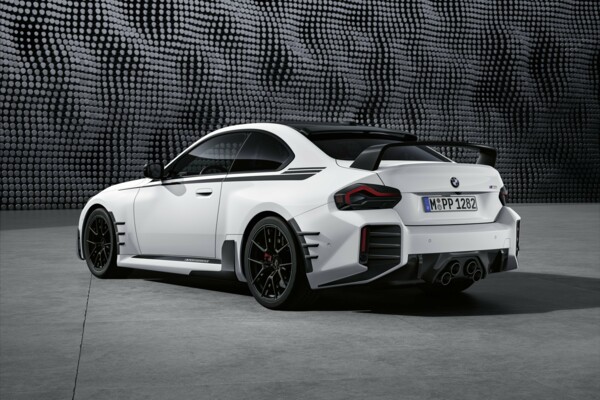 Ein weißes BMW M2 Coupé vor einer modernen, grauen Stuktur-Fassade.