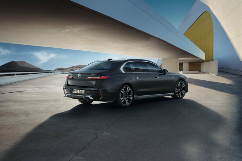 Eine BMW 740i Limousine auf dem Parkdeck eines modernen Gebäudekomplexes im Sonnenschein.