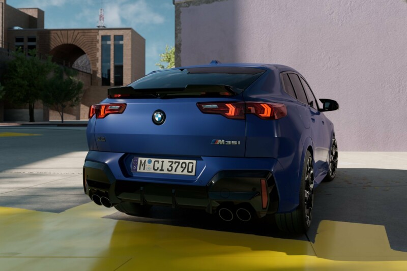 Ein BMW X2 M35i xDrive in der Rückansicht auf einem Stellplatz neben einem modernen Gebäude.