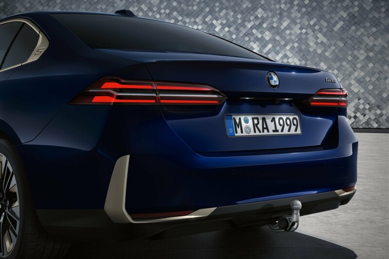 Das Heck einer BMW 520i Limousine vor einer Mosaik-Fotokulisse.