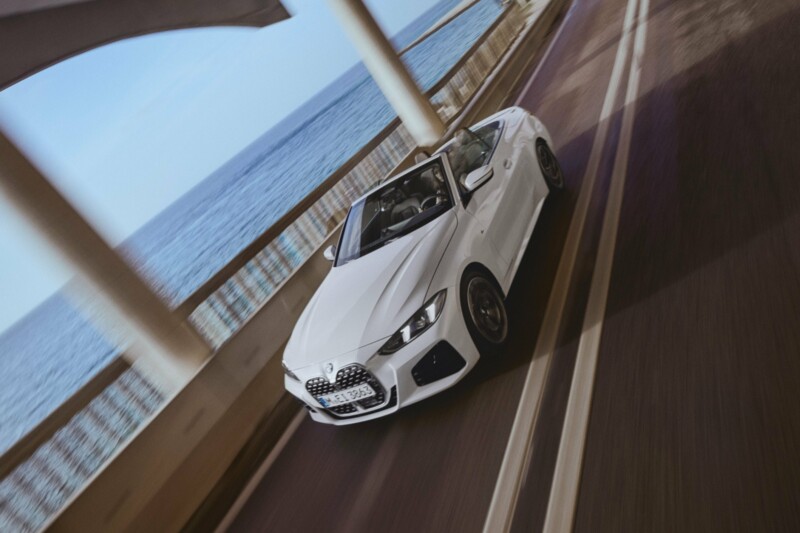 Ein weißes BMW 430i Cabrio während der Fahrt auf einer Brücke übers Meer.
