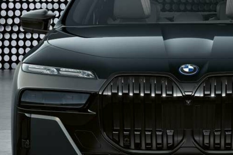 Die Frontansicht eines BMW i7 M70 xDrive mit der typischen BMW-Niere vor einer punktierten Fotokulisse.