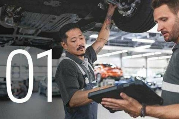 Nummer 1: Service-Mitarbeiter sehen auf ein Tablet während Sie unter einem BMW auf einer Hebebühne stehen.