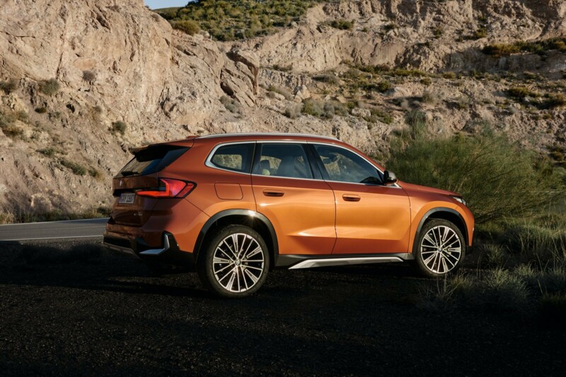 Ein BMW X1 xDrive23d auf einem Parkplatz hoch in den Bergen im Sonnenschein.