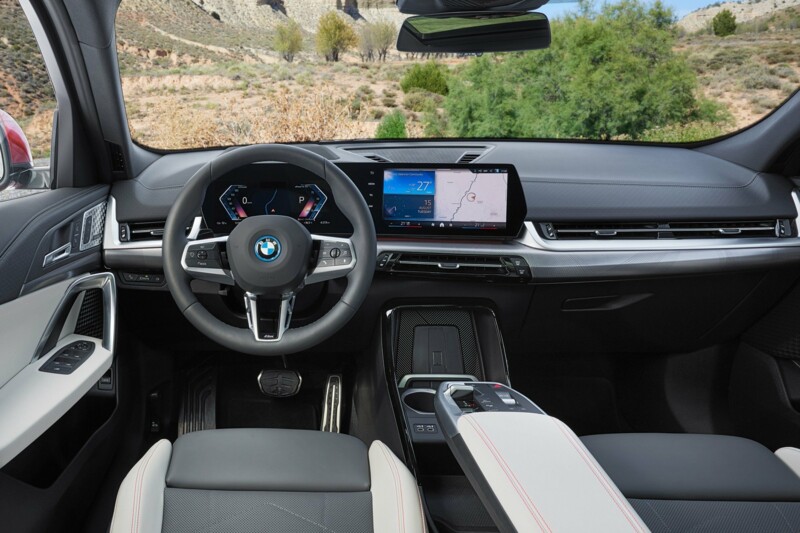 Das Cockpit des neuen BMW iX2 mit Curved Display und Armablage an der Mittelkonsole.