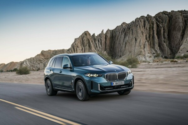 Ein BMW X5 xDrive50e in der Farbe Blue Ridge Mountain metallic fährt auf einer Landstraße in den Bergen.
